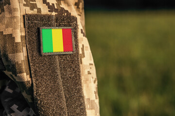 Close up millitary woman or man shoulder arm sleeve with Mali flag patch. Troops army, soldier camouflage uniform. Armed Forces, empty copy space for text
