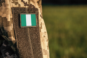 Close up millitary woman or man shoulder arm sleeve with Nigeria flag patch. Troops army, soldier camouflage uniform. Armed Forces, empty copy space for text
