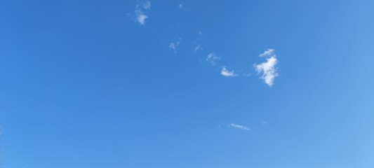 Bright sky above. Spring sunny day, white clouds slowly float in the blue sky. They hang at a low...