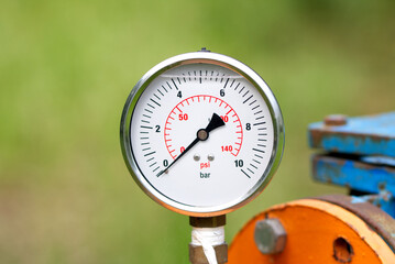 Close up of manometer measuring water pressure. Pipes and valves at industrial plant.