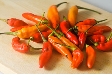 Several red and yellow chilies on a wooden cutting board