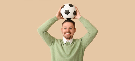 Happy man with soccer ball on beige background