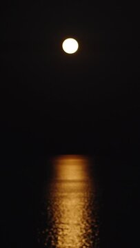 Strawberry supermoon over the sea. Reflection on the water. The boat sails in the light of the moon Vertical. Social Media
