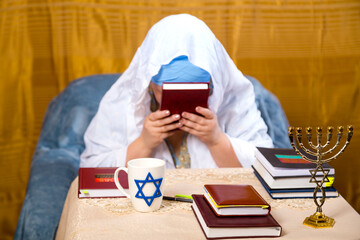 A Jewish woman in a Kisui Rosh headdress and a prayer veil kisses the siddur.