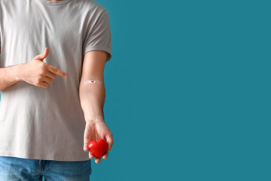 Young blood donor pointing at applied medical patch on blue background