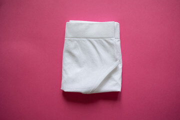 Folded white panties on a pink background. Step 4. Storage by method, organization, closet, underwear, minimalist briefs. Step-by-step folding of panties. Mockup. Briefs. Stacked cotton underwear