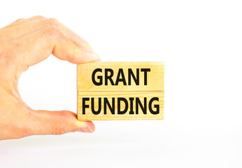 Grant funding symbol. Concept words Grant funding on wooden blocks. Beautiful white table white background. Businessman hand. Business and grant funding concept. Copy space.