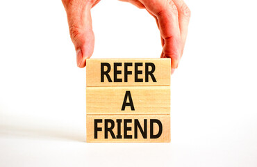 Refer a friend symbol. Concept words Refer a friend on wooden blocks on a beautiful white table white background. Businessman hand. Business and refer a friend concept. Copy space.