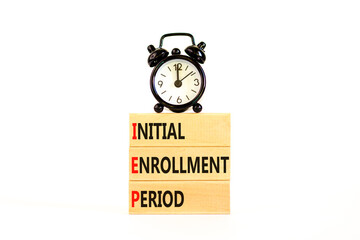 IEP symbol. Concept words IEP Initial enrollment period on beautiful wooden block. Black alarm clock. Beautiful white table white background. Medical IEP Initial enrollment period concept. Copy space.