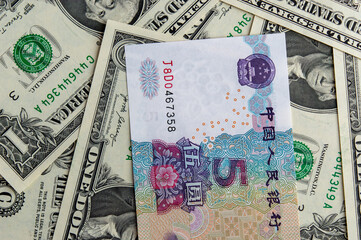 Half view of a 5 yuan banknote, with a composition below consisting of 1 USD bills arranged in an artistic manner.