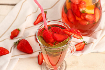 Glass and jug of tasty strawberry juice on white wooden table