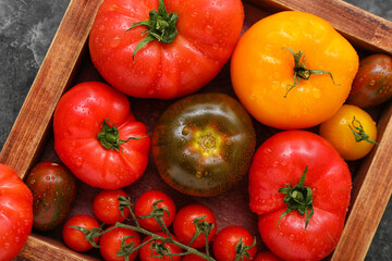 Wooden box with different fresh tomatoes, closeup
