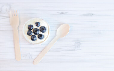 Cream with blueberries in the center. White bowl of Greek yogurt and fresh berries on a light wooden background, top view. Dessert