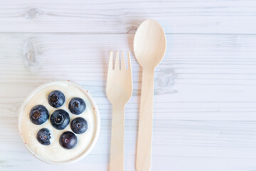 Cream with blueberries in the center. White bowl of Greek yogurt and fresh berries on a light wooden background, top view. Dessert