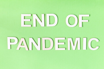 Phrase End of pandemic, wooden letters on green background