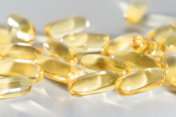 Fish Oil Omega 3 on white background, vitamin D yellow supplement gel capsules, macro shot
