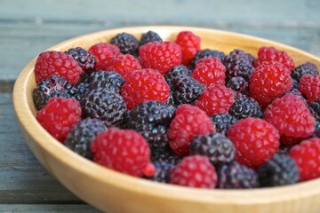 Mix of red and black raspberries in a wooden bowl.