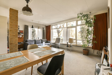 a living room with couches, chairs and a table in the middle of the room there is a plant hanging on the wall
