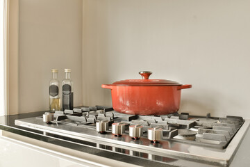 a pot on top of a stove with some cooking uts in front of it and an empty bottle next to it