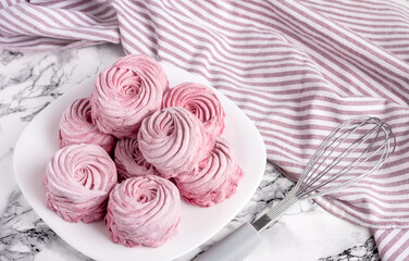 tasty homemade zephyr marshmallows with blackberries taste inside whisk wires or in fork,black gray tiles background,kitchen towel.tea in cup and kettle,marshmallow on plate.close up texture macro
