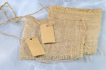Blank tag tied with natural material string. Price tag, gift tag, sale tag, address label on Brown coarse sackcloth texture, burlap texture background, sack Texture.