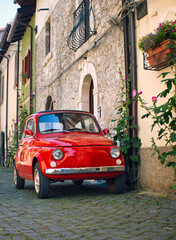 Italy. A tiny red vintage Italian car parked in an Italian town area - obrazy, fototapety, plakaty