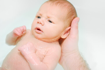 A young father bathes his newborn baby. Parenthood.