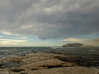 Paesaggio marino in tempesta con rocce e nuvole in tempesta sullo sfondo