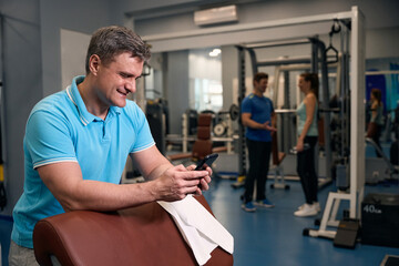 Fototapeta na wymiar Joyous gym-goer reading text message on smartphone after workout