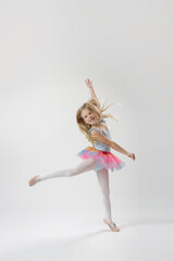 Fototapeta na wymiar Studio portrait of beautiful little ballerina wearing colorful tutu skirt and pink ballet flats
