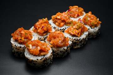 Freshly made sushi roll with sesame and caramelized onions on black background