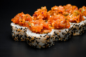 Closeup view on freshly made sushi roll with sesame and caramelized onions on black background