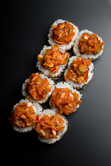 Freshly made appetizing asian roll with sesame and caramelized onions on black background