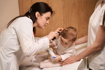 Obraz na płótnie Canvas Experienced otolaryngologist examining eardrum of little baby