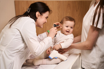 Friendly ENT doctor conducting ear examination on little child