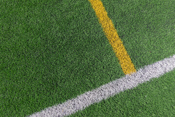 Green artificial grass turf soccer football field background with white and yellow line boundary....