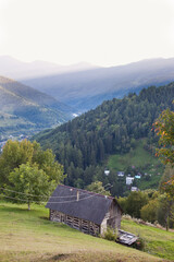 Wooden house on a slope against the backdrop of mountains. Rural landscape with mountain and village view
