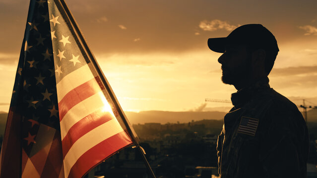 Silhouette of Military Salute of soldier for memorial day against flag at sunset