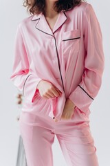 Stylish curly woman wearing pink silk pijama.