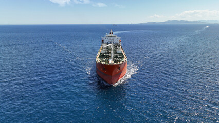 Aerial drone photo of huge crude oil tanker assisted by tug boat cruising open ocean deep blue sea