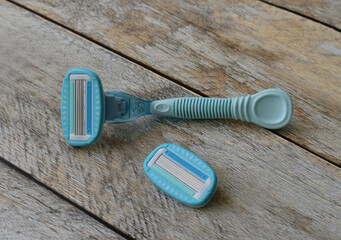 Women's blue razor lies on wooden background