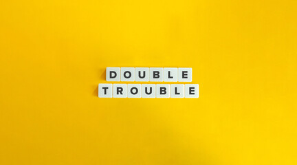 Double Trouble Phrase on Block Letter Tiles on Yellow Background. Minimal Aesthetics.