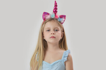 Studio portrait of beautiful bonde little girl wearing unicorn headband
