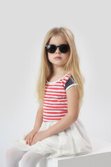 Studio headshot of beautiful 5 years old girl with black sunglasses and long blonde hair