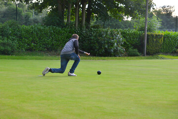 Young man Crown green bowling outdoors, rolling his bowl  towards  the Jack in a competition..