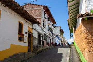 Fototapeta na wymiar Streets of a town in Colombia, where you can see people walking through colored houses. Town in the mountains of Latin America.
