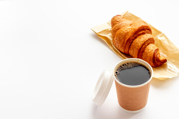One disposible paper cup of coffee to go with croissant
