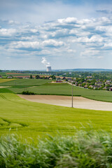Fototapeta na wymiar Centrale nucléaire à l'horizon avec des champs et des villages