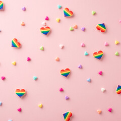 LGBTQ+ support square concepts represented by rainbow-colored parade accessories such as heart pin badges viewed from above on a pastel pink background
