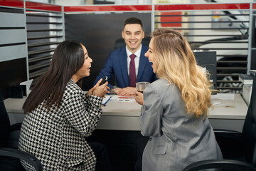 Two happy young women and a man in office area